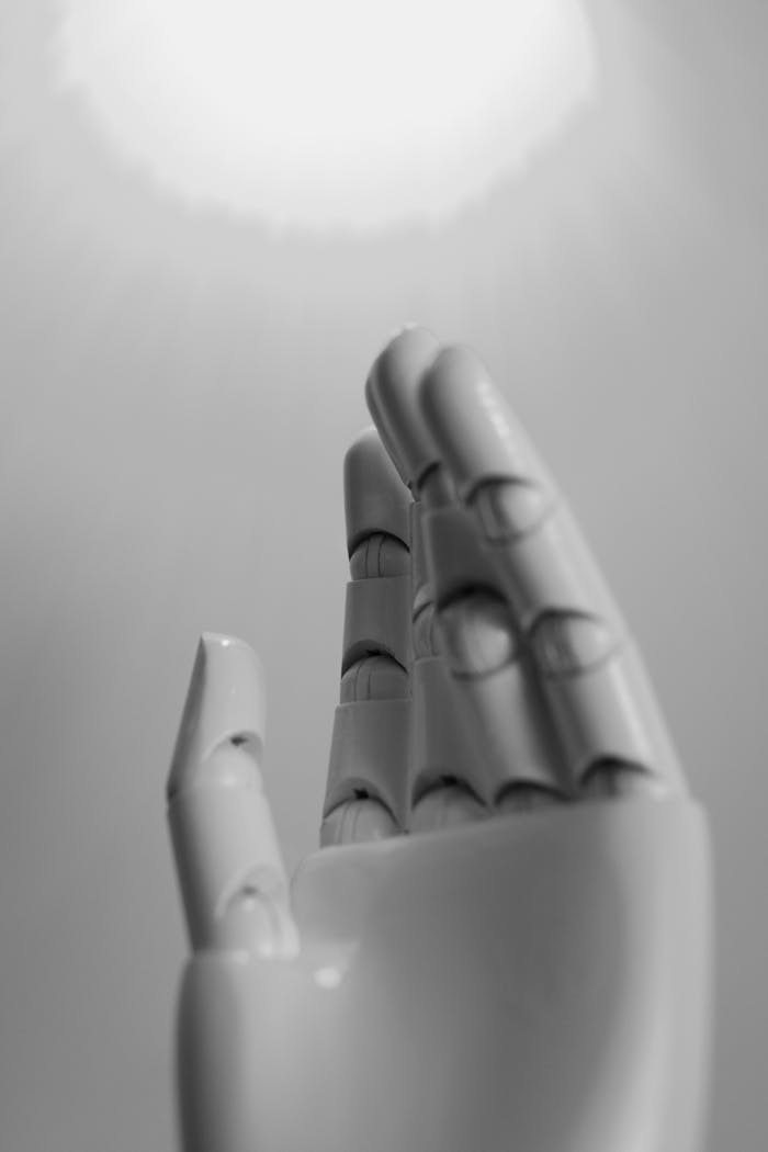 A monochrome close-up of an expressive robot hand reaching upwards.